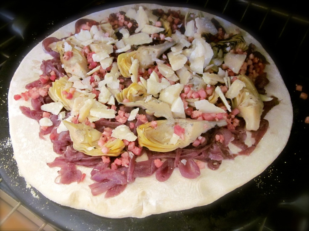 After preheating the oven to a toasty 475 degrees, I transferred my pizza tiooed with precooked pancetta lardons, roasted artichoke hearts and Parmigiano Reggiano Cheese.