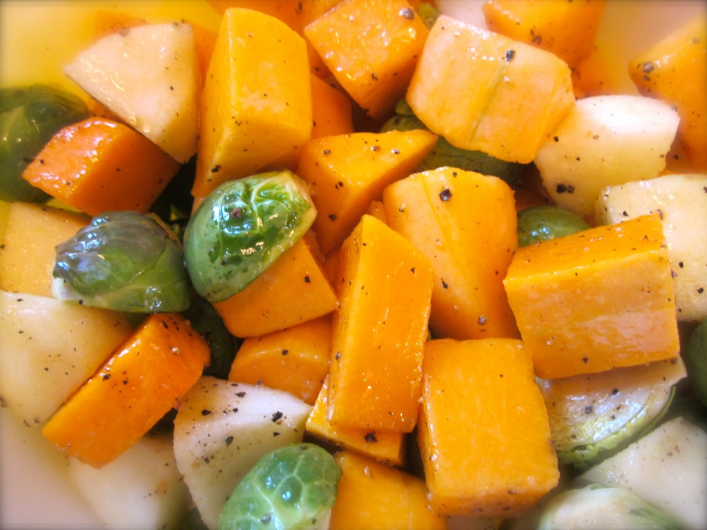 The cubed squash, apples, halved Brussels sprouts, olive oil, salt and pepper are  easily and simply mixed together.
