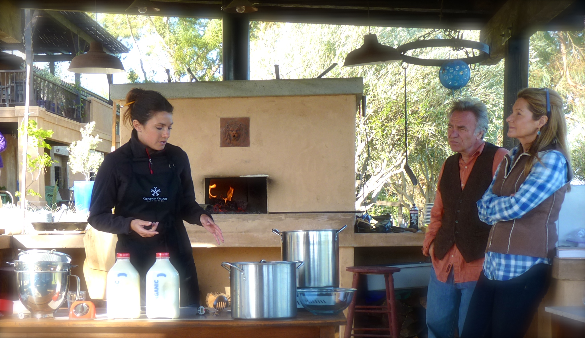 The most difficult thing about making ricotta cheese in an outdoor kitchen on a windy day is to keep the burner's flame lit. Brigit and her husband, Casey, try to block the wind! 