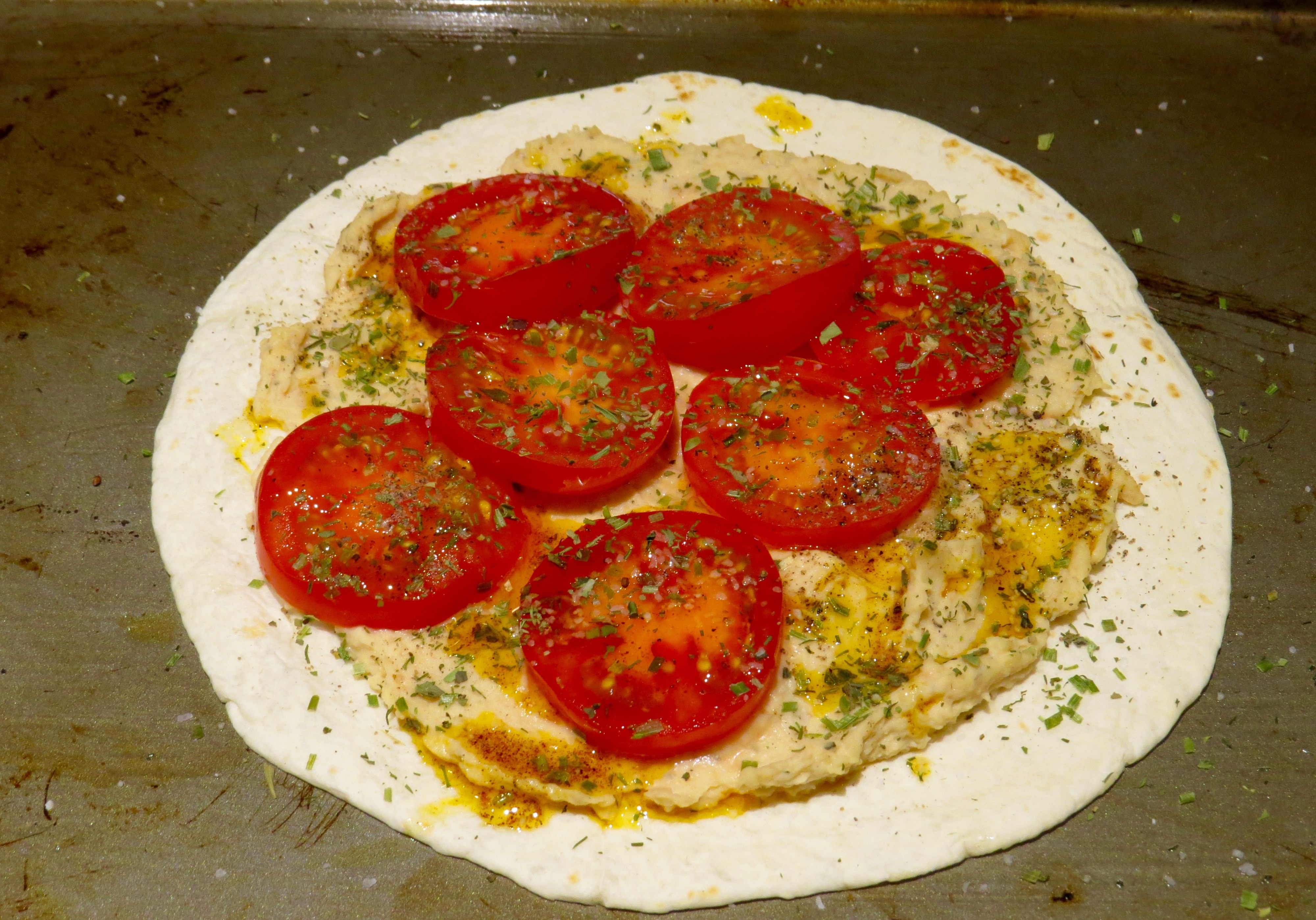 Lunch - Baked Tostadas: Flour Tortilla, hummus spread, sliced tomatoes, chopped herbs. Ready for a 400 degree oven for 10 minutes.