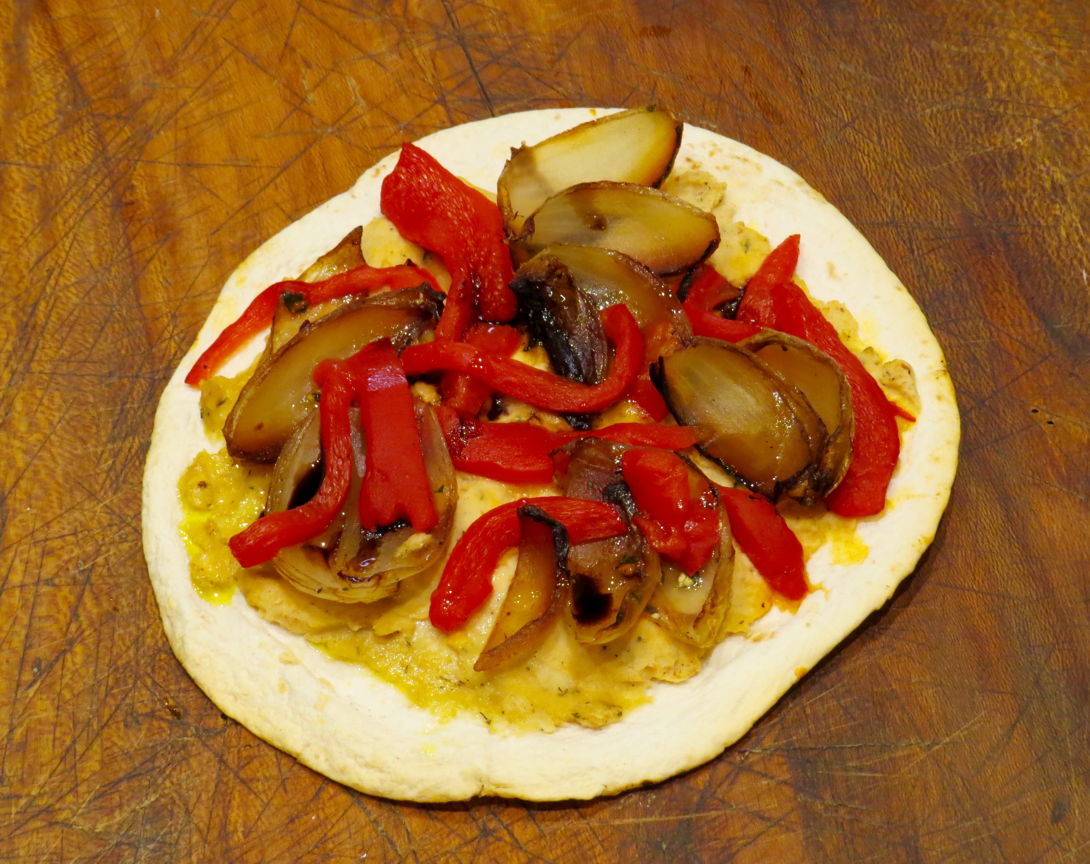 Baked Tostadas: Flour tortilla, hummus spread, roasted red-pepper slices and leftover carmelized onions from my last piece of onion tart. Just pulled from the oven - it's lunch. 